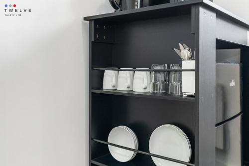 a black shelf with plates and cups on it at Bright & Modern Room in Brixton - Shared Bathroom in London