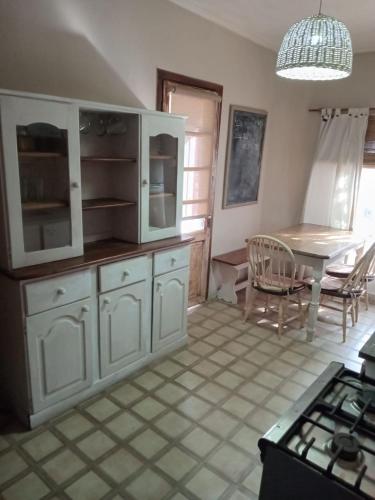 a kitchen with white cabinets and a table and a dining room at Paz in Tandil