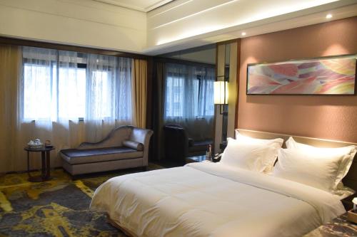 a bedroom with a large white bed and a chair at Ramada Foshan Hotel in Foshan