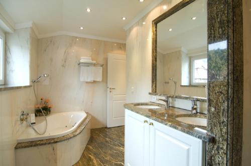 a bathroom with two sinks and a tub and a large mirror at Hotel Ochsen Stuttgart in Stuttgart