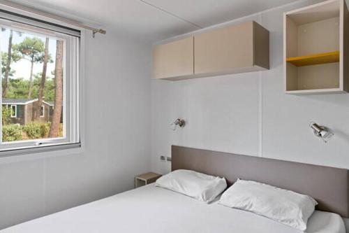 una camera da letto bianca con un letto e una finestra di Camping Le Domaine de la Marina a Messanges