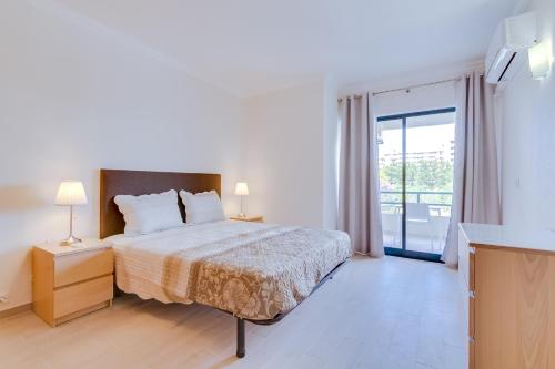 a white bedroom with a bed and a balcony at Tália - City Center - Vilamoura in Vilamoura