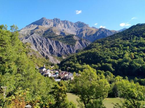 ein Dorf in einem Tal mit Bergen im Hintergrund in der Unterkunft Gite Noryema Chaleureux T1, 40m2 in Entraunes