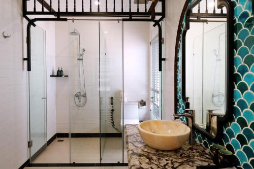 Un baño con lavabo y ducha de cristal. en Indochine Hotel Hoi An, en An Bàn (2)