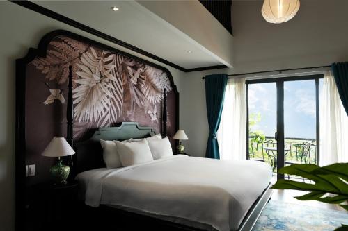 Un dormitorio con una cama grande con una ventana grande. en Indochine Hotel Hoi An, en An Bàn (2)