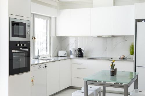 eine weiße Küche mit einem Tisch und einer Mikrowelle in der Unterkunft Miral Beachside 5 - by HD Properties in Caliços