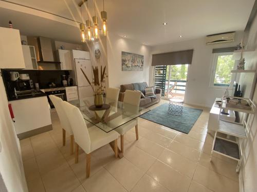 a kitchen and living room with a glass table and chairs at Neptuno IV - Vilamoura in Quarteira