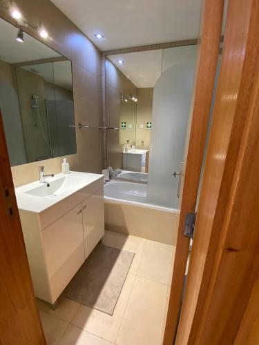 a bathroom with a sink and a tub and a mirror at Neptuno IV - Vilamoura in Quarteira