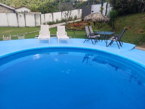 - une piscine bleue avec des chaises et une table dans l'établissement Recanto da Totoquinha, à Juiz de Fora