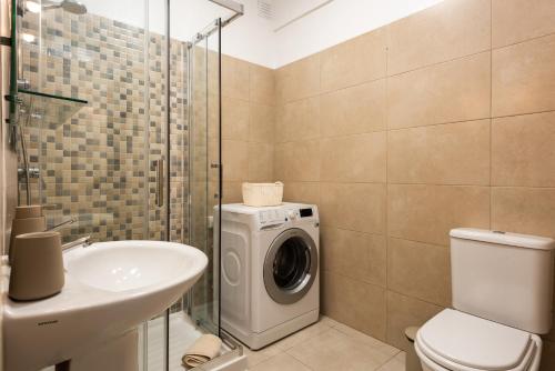 ein Badezimmer mit Waschmaschine und Waschbecken in der Unterkunft Maresia - Front beach - Quarteira in Vilamoura