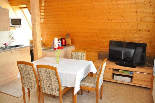 ein Esszimmer mit einem Tisch mit Stühlen und einem Fernseher in der Unterkunft Ferienwohnung Neubert in Wolkenstein