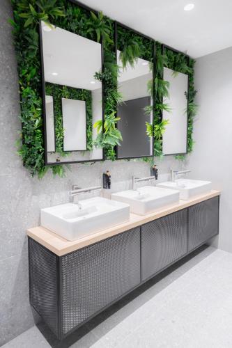 a bathroom with two sinks and two mirrors at WE Hotel EXPO Prague in Prague