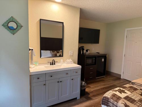 ein Badezimmer mit Waschbecken und Spiegel und einem Bett in der Unterkunft Winthrop Inn in Winthrop