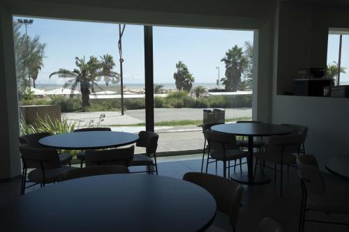 una habitación con mesas y sillas y una ventana grande en Hotel Seaview, en Rímini