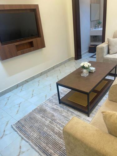 un salon avec une table basse et une télévision à écran plat dans l'établissement سفانة هلا للشقق المخدومة, à Hafr Al Baten