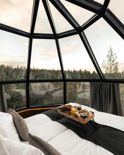 un vassoio di cibo seduto su un letto di fronte a una finestra di SkyView Igloo Resort a Rovaniemi