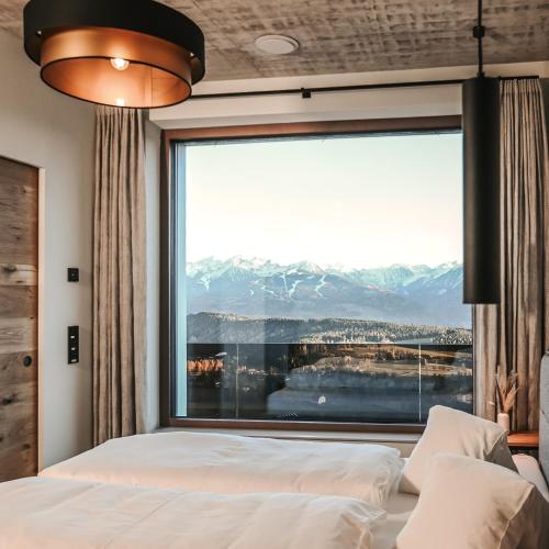 a bedroom with a large window with a mountain view at Alpin Chalet Dachsteinhaus in Ramsau am Dachstein