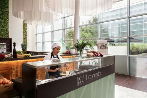 a woman standing in a kitchen preparing food at Sheraton Milan Malpensa Airport Hotel & Conference Centre in Ferno