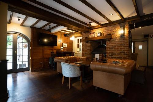 a living room with leather furniture and a brick wall at The Princess Royal in Farnham