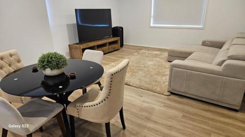 a living room with a table and chairs and a couch at Cosy Home in Melton South in Melton South