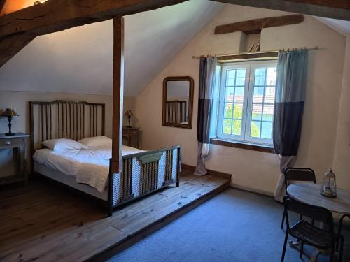 Schlafzimmer mit einem Bett, einem Fenster und einem Tisch in der Unterkunft Les Vergnes in Saint-Pardoux-le-Neuf