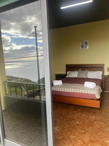 ein Schlafzimmer mit einem Bett und einem Balkon in der Unterkunft Fernanda's House in Ribeira Brava