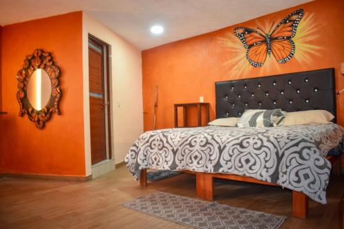 - une chambre dotée d'un lit avec un papillon sur le mur dans l'établissement Departamento céntrico con terraza, à Mineral de Angangueo