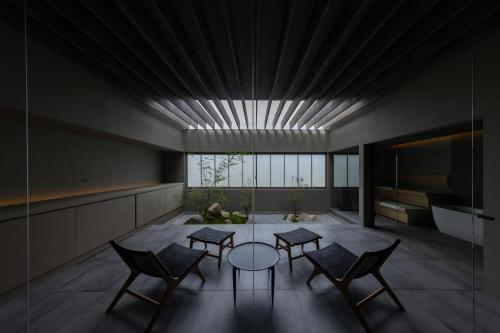 ein Wohnzimmer mit einem Tisch, Stühlen und einer Badewanne in der Unterkunft villa OCTOPORTO yobuko in Karatsu