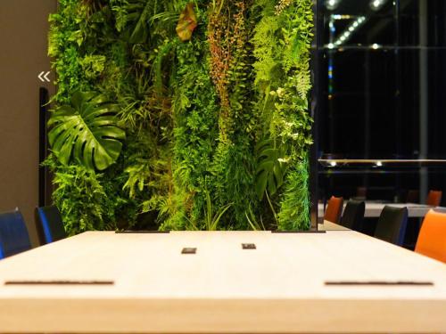 una mesa con una pared vegetal al fondo en Travelodge Kyoto Shijo Omiya, en Kioto