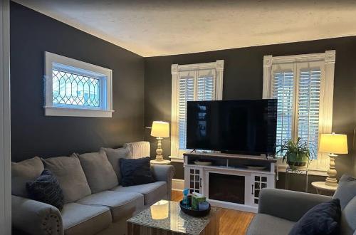 a living room with a couch and a flat screen tv at The Hamilton Harbor House in Oswego