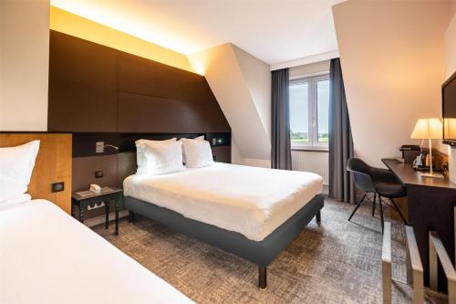 a hotel room with two beds and a desk at Hotel L'Europe Colmar, BW Signature Collection in Colmar