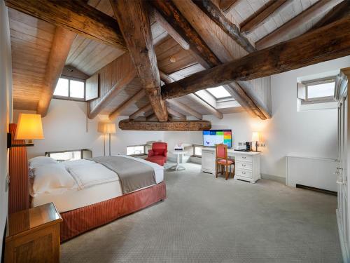 a bedroom with a bed and a desk with a television at Grand Hotel della Posta, WorldHotels Distinctive in Sondrio