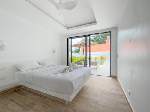 una camera bianca con un letto e una grande finestra di Stylish 3BR Pool Villa Lawan Villa (LWV1) a Ban Na Bon