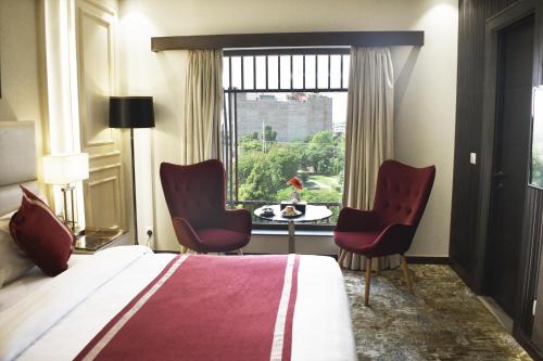 une chambre d'hôtel avec un lit, deux chaises et une fenêtre dans l'établissement Best Western Plus Grand Multan, à Multan
