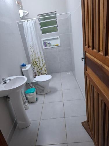 a white bathroom with a toilet and a sink at Casa Petar Betari in Iporanga