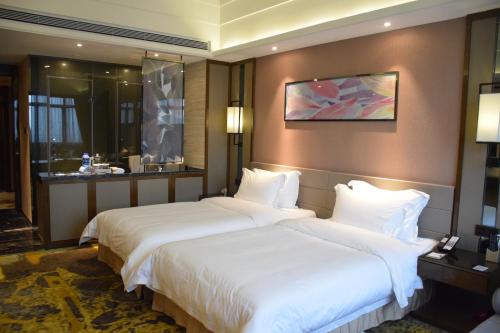 two beds in a hotel room with white sheets at Ramada Foshan Hotel in Foshan