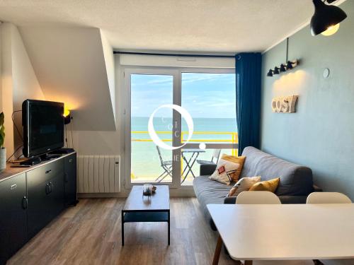een woonkamer met een bank en uitzicht op de oceaan bij COC - Le Panorama in Wissant