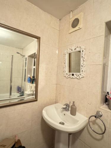 ein Badezimmer mit Waschbecken und Spiegel in der Unterkunft Comfort rooms near City Airport in London