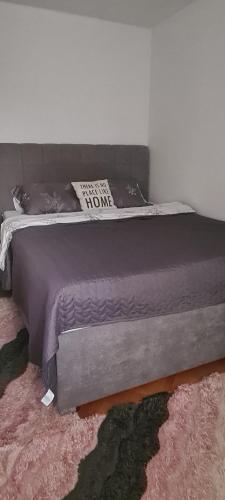 una cama grande en un dormitorio con una colcha gris en Ali app, en Travnik