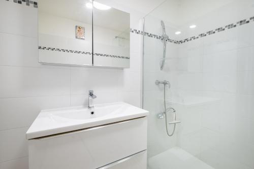 a white bathroom with a sink and a shower at meublé tourisme 3 étoiles vue mer in Golfe-Juan