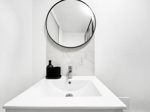 a bathroom sink with a round mirror on the wall at Loft cosy, Canapé-lit & Mezzanine, cœur de Cambrai in Cambrai