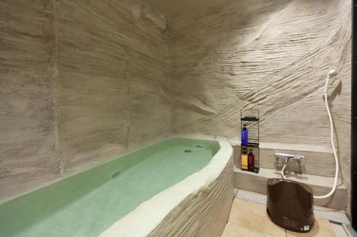 uma casa de banho com uma banheira numa parede de pedra em Yukkura Inn em Aizuwakamatsu