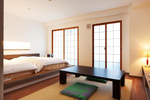 um quarto com uma cama, uma mesa e janelas em Yukkura Inn em Aizuwakamatsu