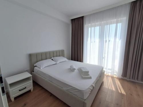 a bedroom with a white bed and a large window at Apartament Suceava in Ipoteşti