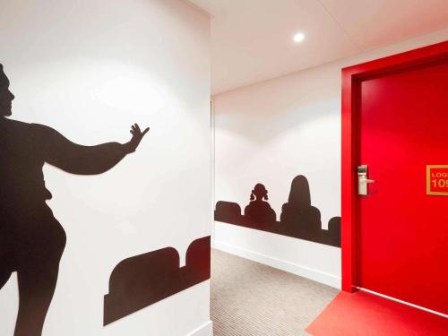 una puerta roja en una habitación con un mural de una mujer en ibis Styles Montpellier Centre Comedie, en Montpellier