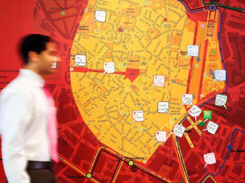 un hombre caminando delante de un mapa en ibis Styles Montpellier Centre Comedie, en Montpellier