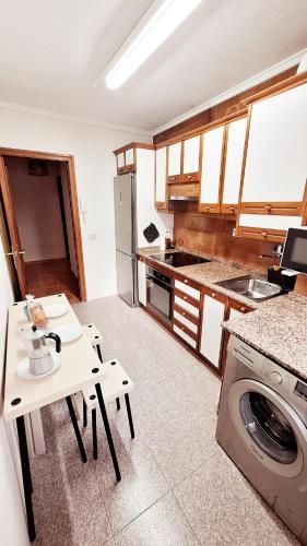 a kitchen with a table and a washing machine at Jona Candás Asturias in Candás