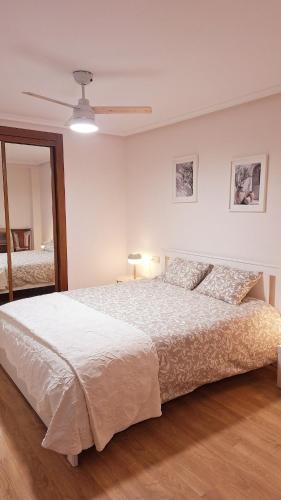 a white bedroom with a bed and a ceiling fan at Jona Candás Asturias in Candás