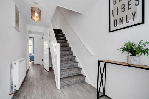 a staircase in a home with white walls and wooden floors at Bella Homes-Spacious 4 bedroom Modern Town house Romford in Romford