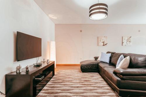 a living room with a leather couch and a flat screen tv at Modern & Elegant 2 bedroom in Amadora by GT House in Amadora
